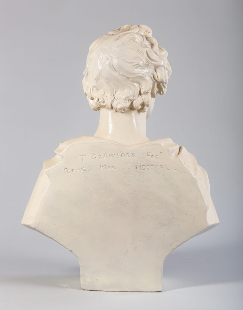 Glazed ceramic bust of a man with short, curly hair and a mustache, draped in a toga.