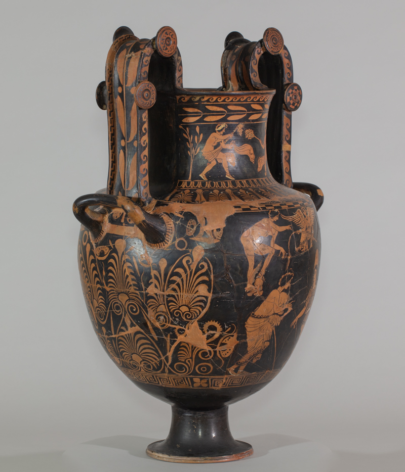 Alternate view of An ancient, ornately-decorated, two-handled, greek vase. The black background is decorated wth assorted brownish-orange floral motifs, male youths,satyrs and a winged figure on the base and neck.
