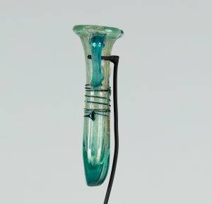 Alternate view of An ancient narrow, two-handled glass vessel tinted teal. The vessel is a long pipe shape folded in half so the two opening meet at the top.