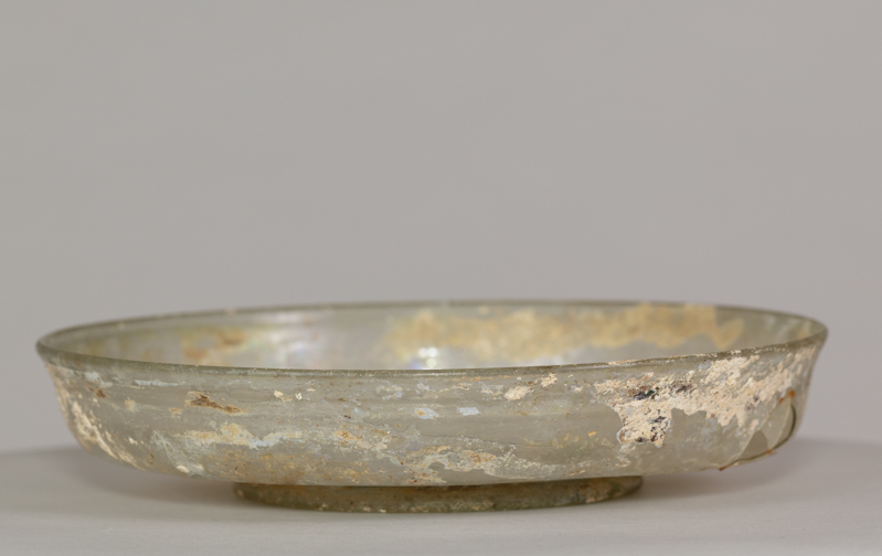 Alternate view of An ancient glass dish mostly transparent after brown and gold paint worn away.