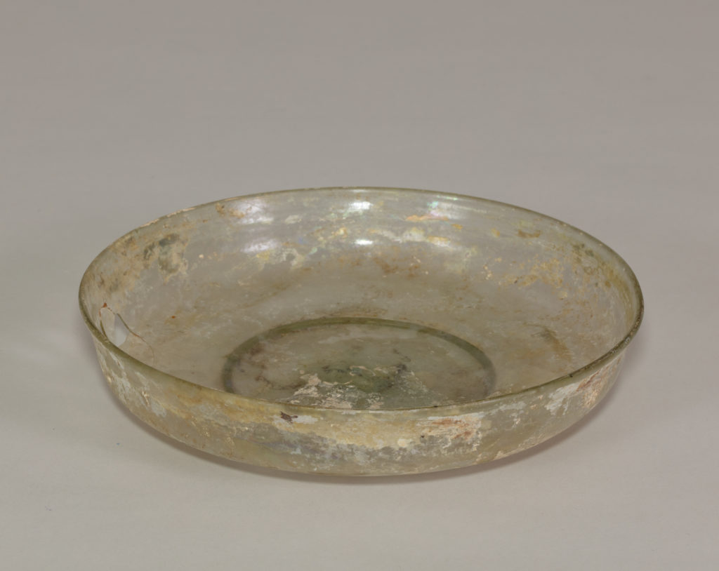 An ancient glass dish mostly transparent after brown and gold paint worn away.