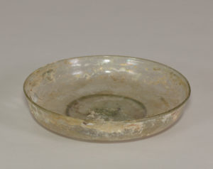 An ancient glass dish mostly transparent after brown and gold paint worn away.