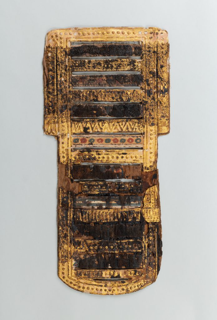 Alternate view of Four sculptural fragments including a mummy mask and three panels with intricate carvings and patterns in gold leaf.