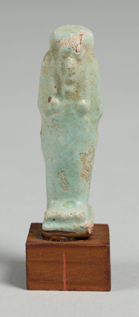 Blue-tinted figurine of a mummy on a wood base.