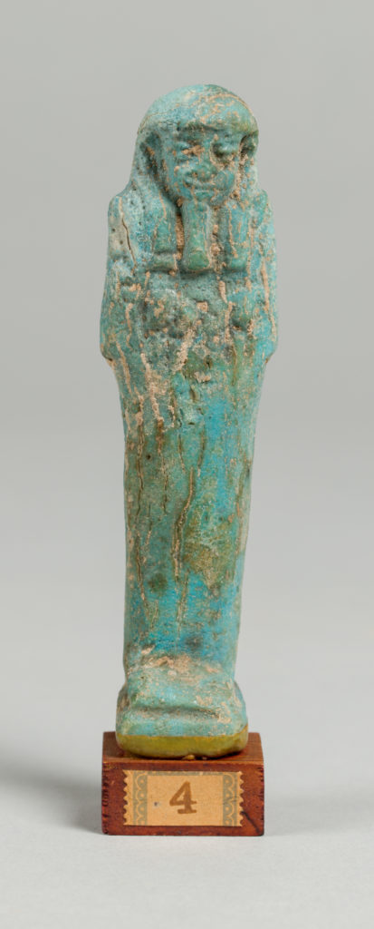 Blue-tinted figurine of a mummy on a wooden base with the number 4.