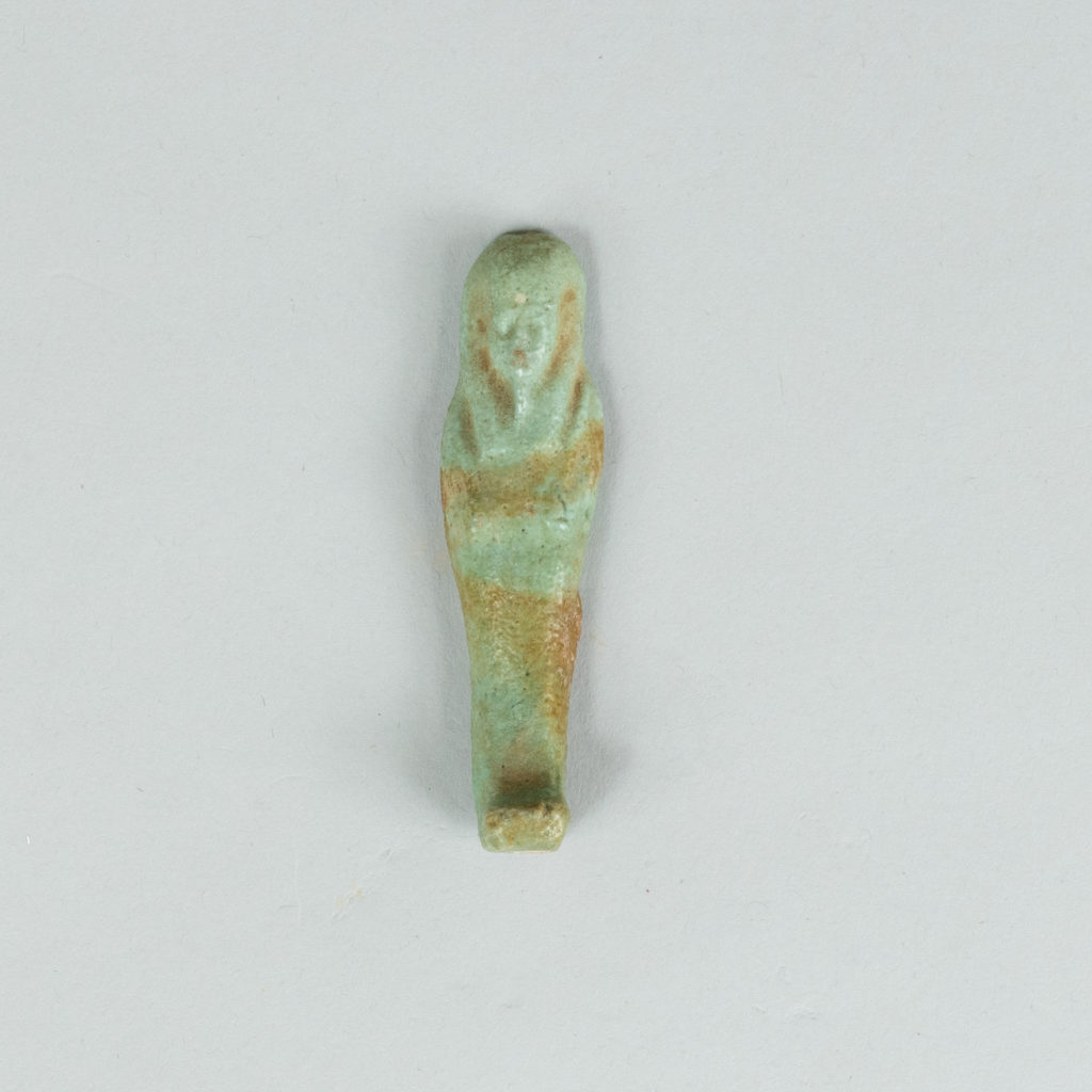 A green tinted ancient Egyptian figurine carved into the shape of a mummy.
