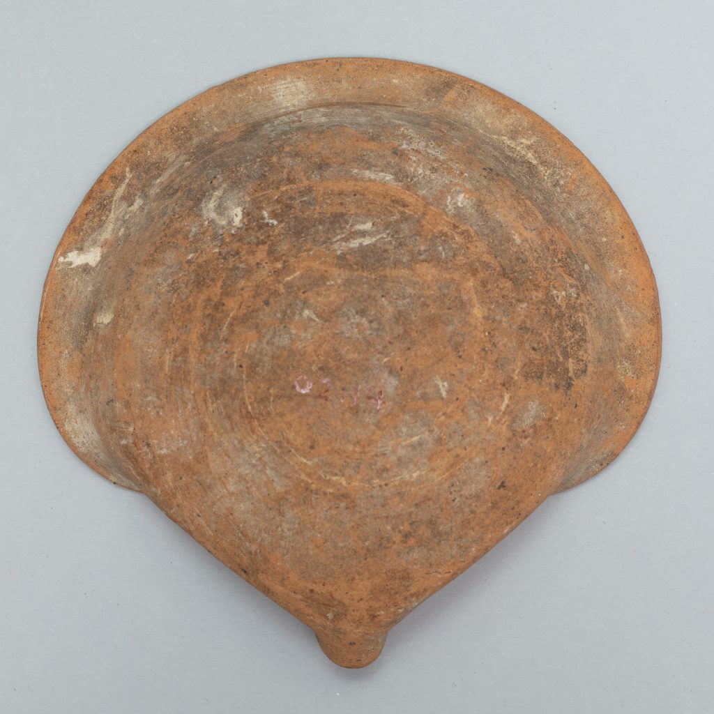Alternate view of Circular terracotta lamp with one side of its lip folded into a curl.