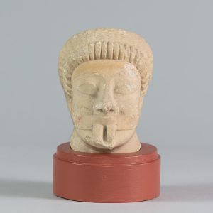Alternate view of White limestone carved head with closed eyes, mounted on a circular platform.