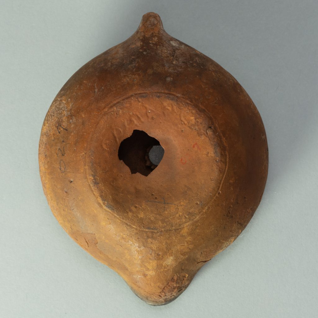Alternate view of Circular terracotta lamp with palmette pattern carved into its surface.