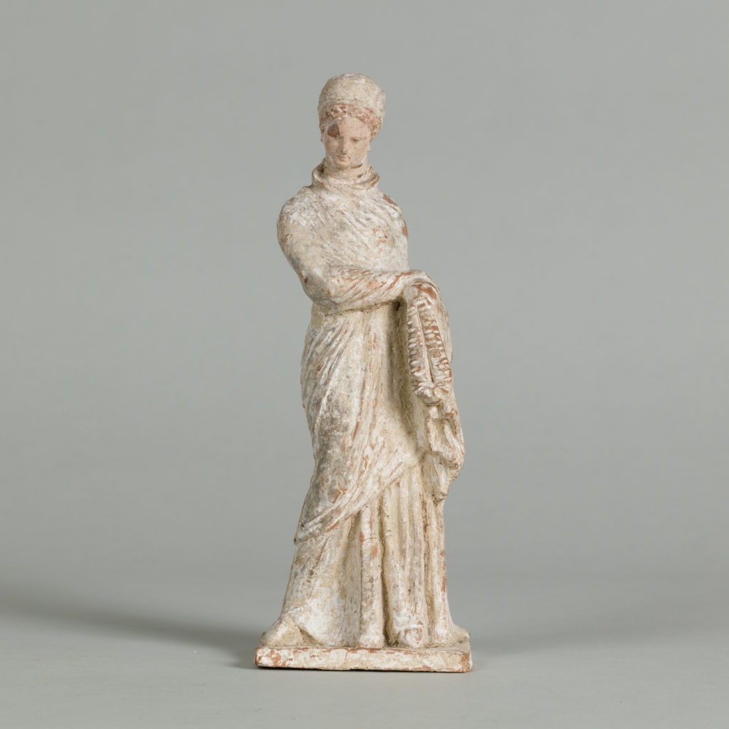 White terracotta statue of a woman wearing a head wrap and a toga, holding a chaplet.
