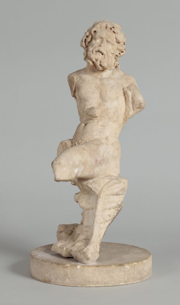 Small, white marble statue of a seated satyr, its arms and legs missing.
