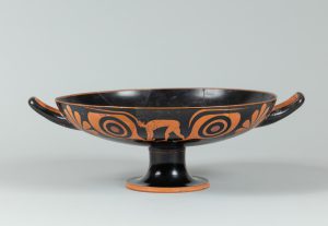Alternate view of Wide, low terracotta cup with two handles, painted with red figures, scalloped shells, and other designs.