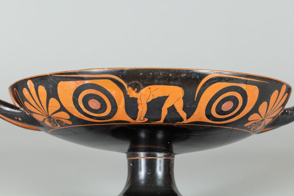 Alternate view of Wide, low terracotta cup with two handles, painted with red figures, scalloped shells, and other designs.