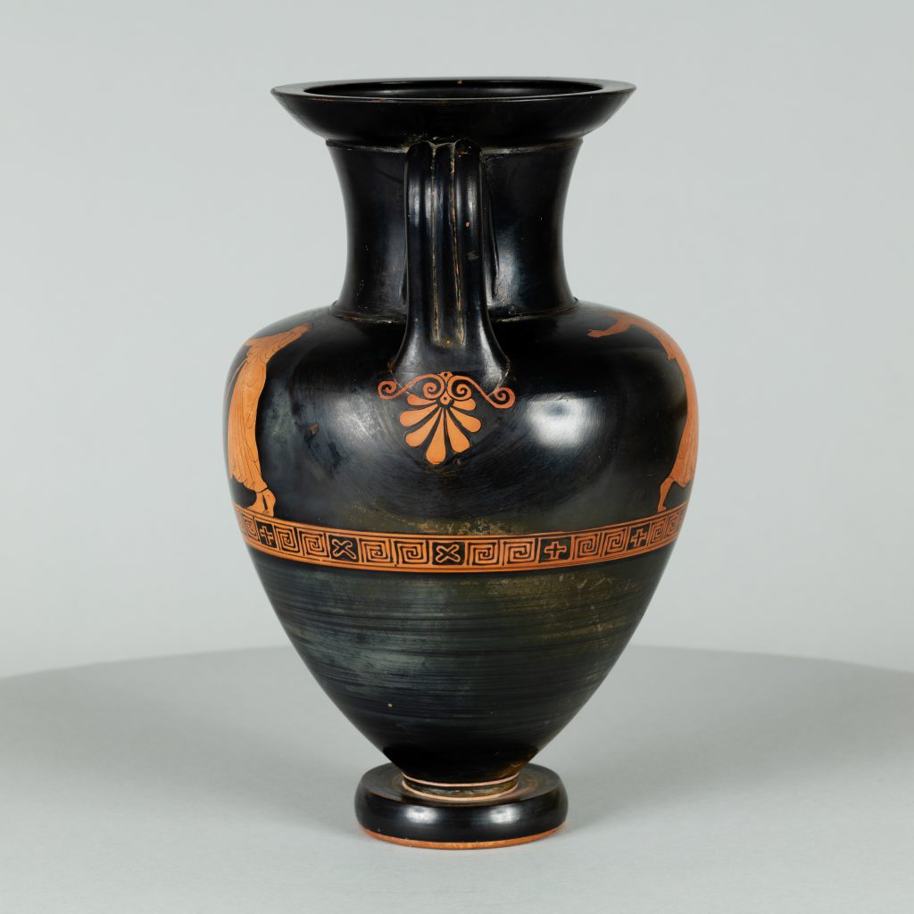 Alternate view of Black terracotta vessel with two handles and red-figure painting depicting a youth playing a flute while another figure observes.