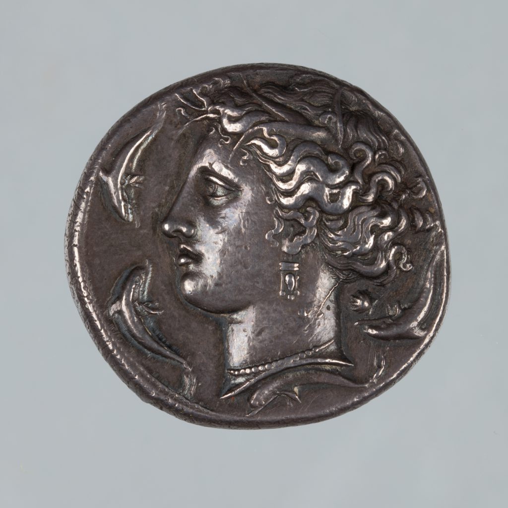 Ancient silver coin featuring the profile of a woman and two small fish.