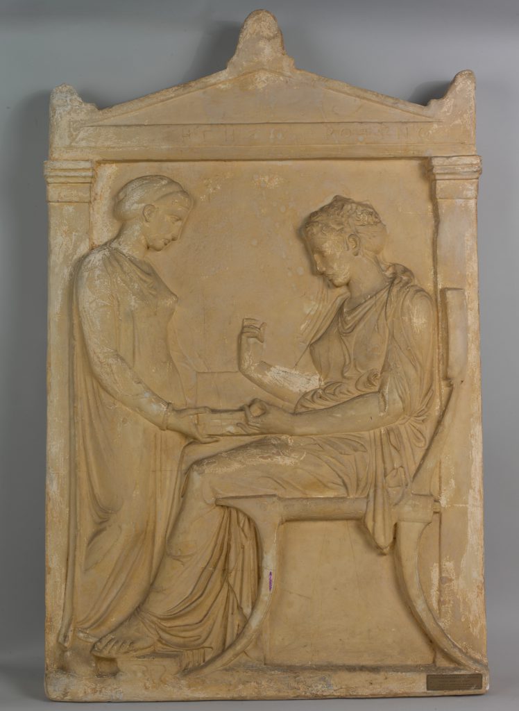 Plaster relief of a standing woman looking down at a seated man.