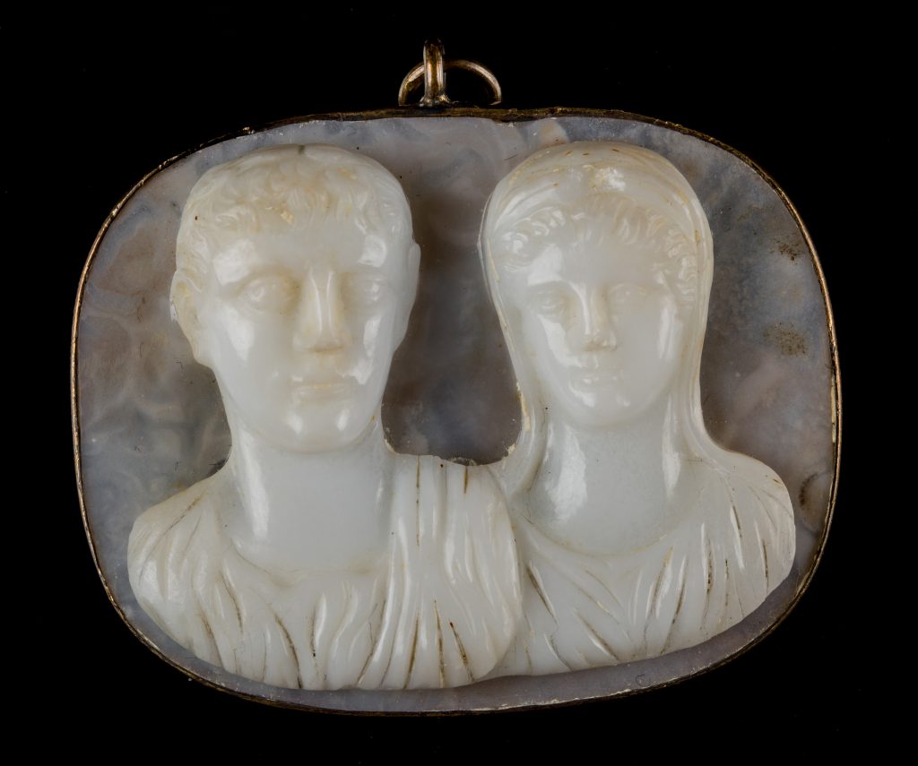 White chalcedony cameo depicting a man a woman, set into an oval pendant.