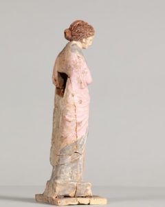 Alternate view of Painted terracotta statue of a woman with red hair, gather her pink and gray robe into her arms.