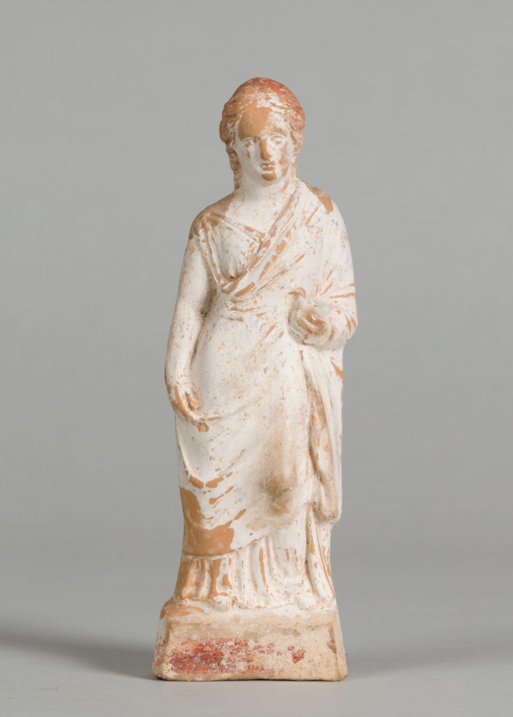 White terracotta statue of a woman wrapped in a toga and holding a dove. Red terracotta shows through parts of the surface.