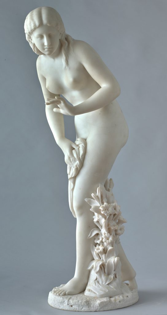 Alternate view of White marble statue of a nude young woman partially covering her bottom half with a sheet, flowers climbing up her left leg.