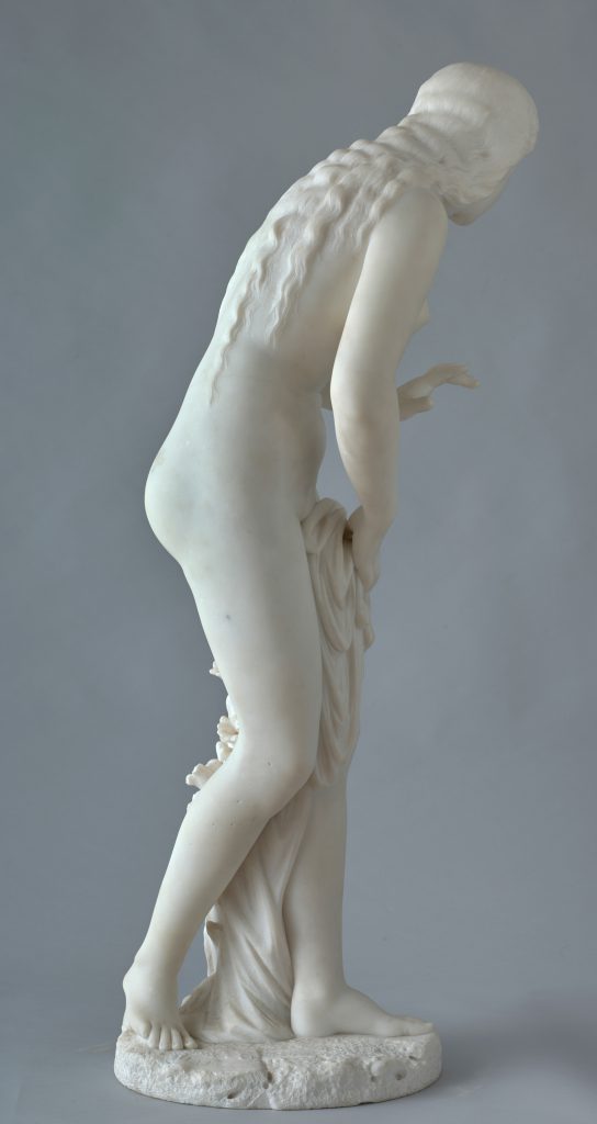 Alternate view of White marble statue of a nude young woman partially covering her bottom half with a sheet, flowers climbing up her left leg.