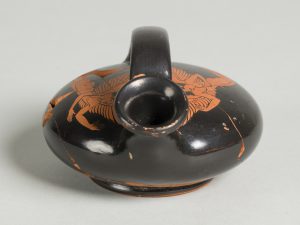 Alternate view of Disc-like terracotta oil flask with a top handle and red-figure painting of a winged figure.