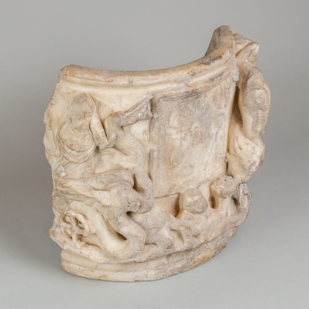 White, marble fragment of an urn with figural carvings in relief.