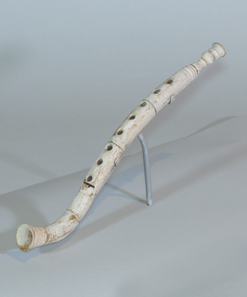 Alternate view of Ivory flute resembling a modern recorder, mounted on a small base.