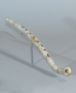 Alternate view of Ivory flute resembling a modern recorder, mounted on a small base.