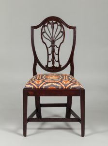Dark mahogany chair with seat upholstered in blue, orange, and gold patterned fabric.
