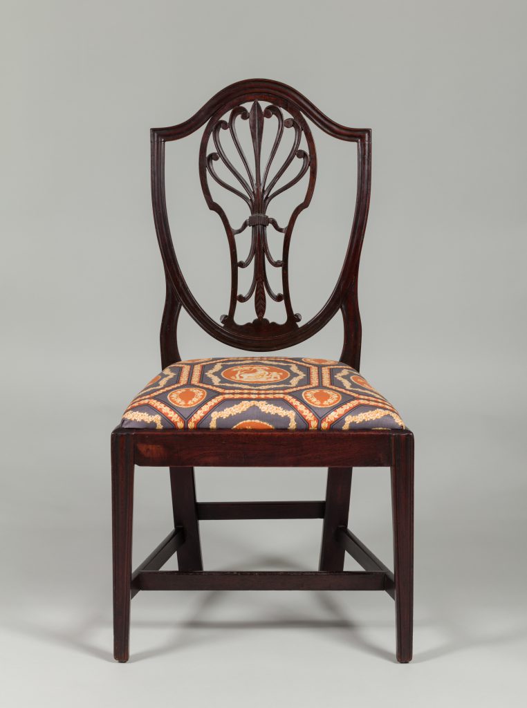 Dark mahogany chair with seat upholstered in blue, orange, and gold patterned fabric.