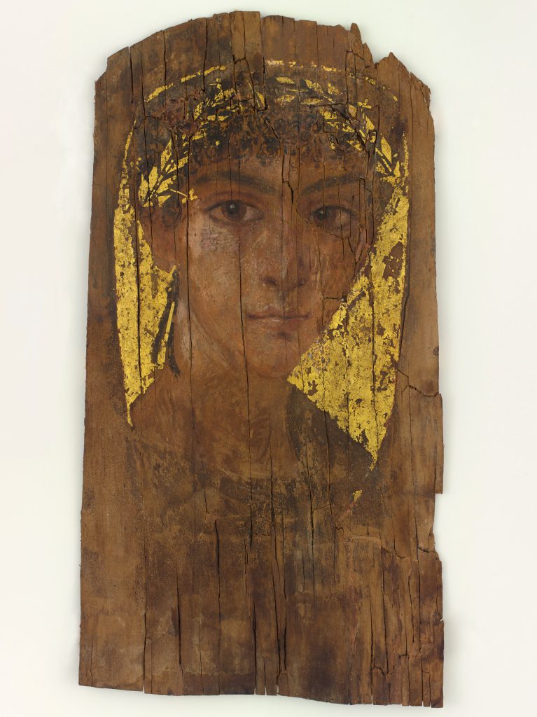 Portrait on wood of a young man's face. He wears a gold wreath and looks directly at the viewer.