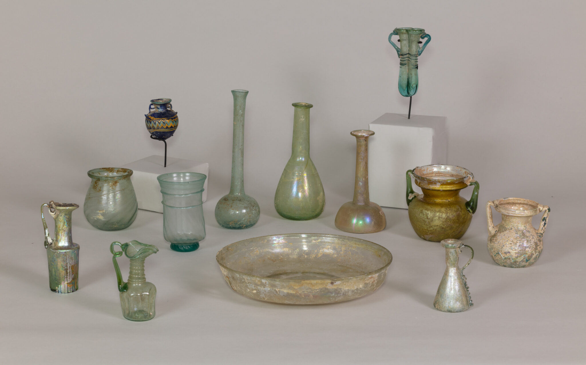 Assorted ancient glass vessels set out for display.