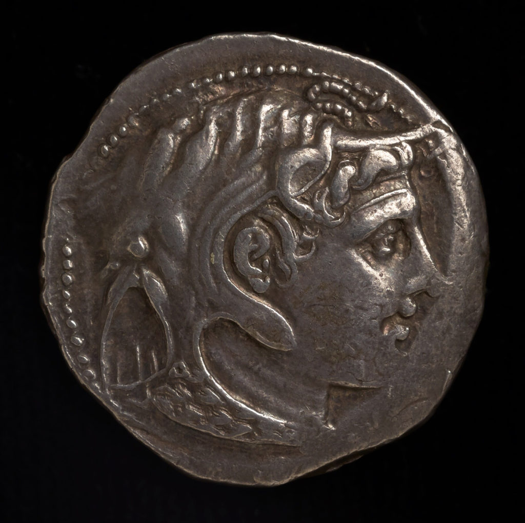 Ancient coin with imperfect edges, featuring a carved profile of a face.