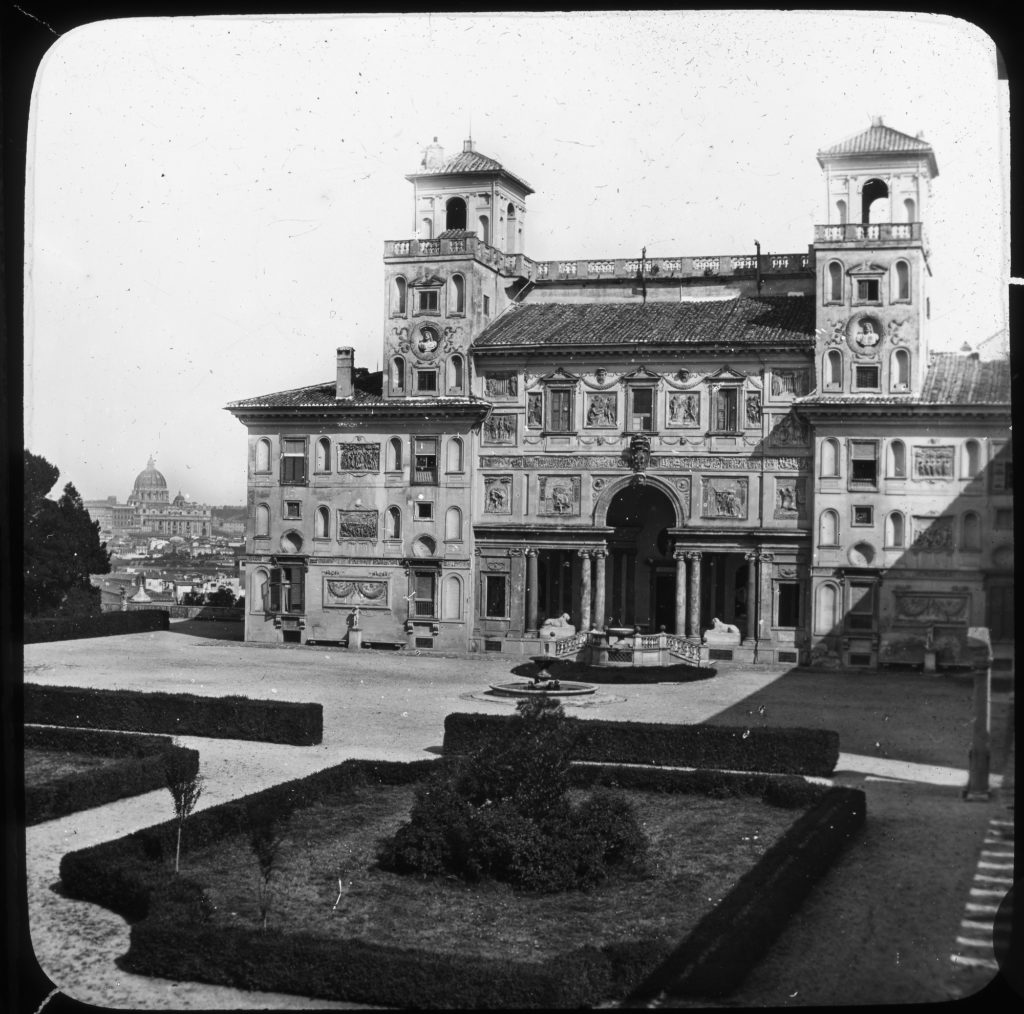 Black and white photo of a grand building set back behind majestic landscaping.